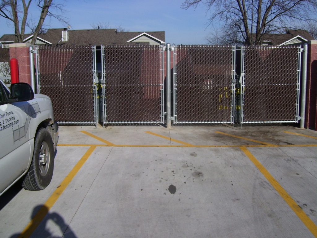 Two sets of double swing gates with privacy slats secure this dumpster enclosure